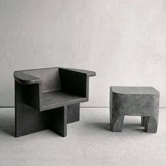 two chairs and a stool made out of concrete are sitting side by side in front of a white wall