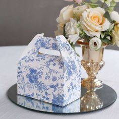 a blue and white box sitting on top of a table next to a vase filled with flowers