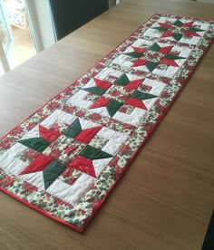 a table runner made with red, green and white quilts on top of a wooden table