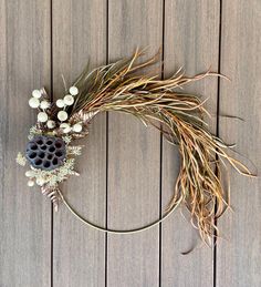 a wreath made out of dried grass and flowers on a wooden decking area with the word love written in it