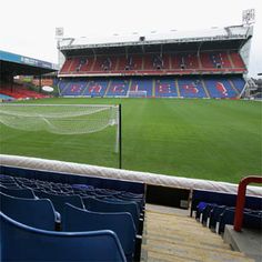 an empty soccer stadium with blue seats and red stands on the sidelines in front of it