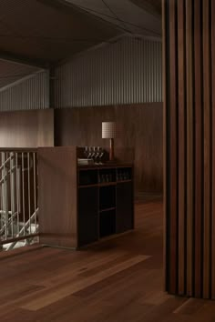 an empty room with wooden floors and bars on the wall, next to a wine rack