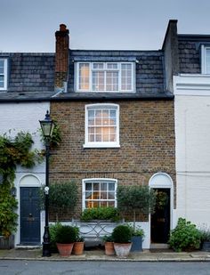 an old brick house with potted plants in front