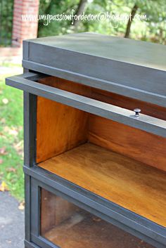 an old dresser is painted gray and has wooden shelves on the bottom, with one drawer open