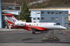 a red and white plane is parked on the tarmac in front of some buildings