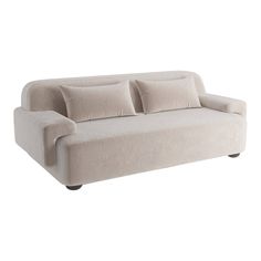 a white couch with four pillows on it's back and two arms, sitting against a