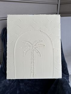 a white piece of art with a palm tree on it's side and blue velvet