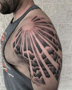 a man with a tattoo on his arm that has sun rays coming out of the clouds