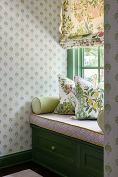 a window seat with pillows on it in front of a green wallpapered room