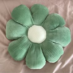 a green flower shaped pillow sitting on top of a bed