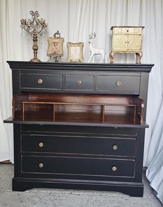 an old dresser has been painted black with gold trimmings and pulls on the drawers