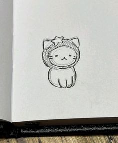 an open book with a drawing of a cat wearing a bow on it's head