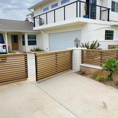 a white house with a wooden fence in front of it and a car parked on the driveway