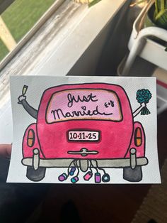 a hand holding up a pink car with the words just married written on it