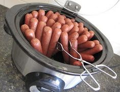 a crock pot filled with hot dogs on top of a counter next to a wall