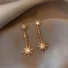 Description: CZ Inlaid Polar Star Boho Dangle Earrings Specifications:Material: Eco-plated Copper, Cubic Zirconia, Artificial Pearl, 18k Gold Species: EarringsSize: 4.4 cm * 1.8 cmWeight: 5 g/pair "Add a touch of celestial charm to your wardrobe with our CZ Inlaid Polar Star Boho Dangle Earrings! These earrings feature a sparkling CZ inlaid polar star design that will make you shine bright like a star. Perfect for adding a fun and playful twist to any outfit!"