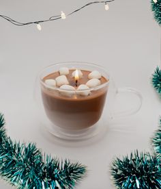 a cup of hot chocolate with marshmallows in it on a white table