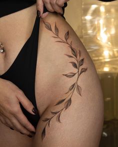 a woman's stomach with a tattoo on the side of her body and leaves