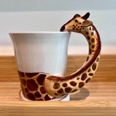 a giraffe shaped coffee cup sitting on top of a wooden table