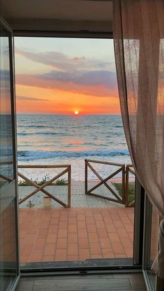 the sun is setting over the ocean as seen from an open door