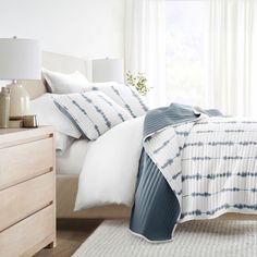 a bed with white and blue comforters in a bedroom