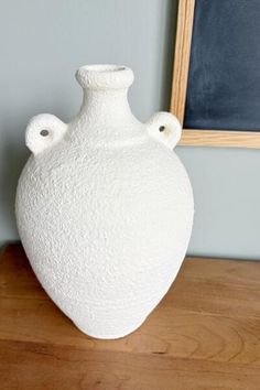 a white vase sitting on top of a wooden table