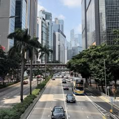 cars are driving down the street in front of tall buildings and palm trees on both sides