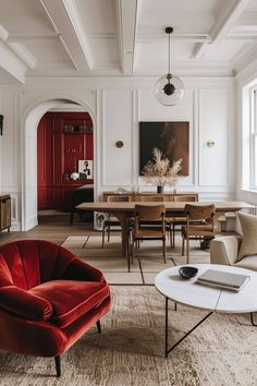 a living room filled with furniture next to a dining room table and two red chairs