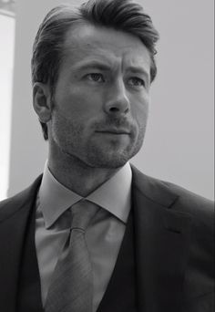 a black and white photo of a man in a suit looking off to the side