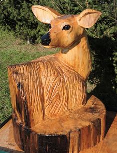 a carved wooden deer sitting on top of a tree stump