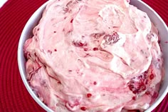 a white bowl filled with food sitting on top of a red place mat next to a knife