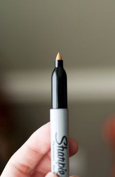 a person holding a black and white pen in their left hand, with the tip pointing upward