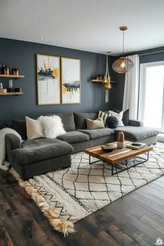 a living room with gray couches and white rugs on the hardwood flooring