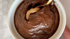 a person holding a spoon in a bowl filled with chocolate