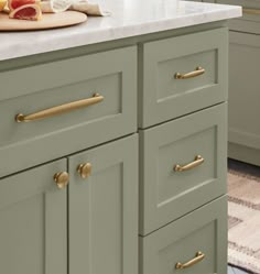 a kitchen with green cabinets and white counter tops, gold pulls on the handles that are brass