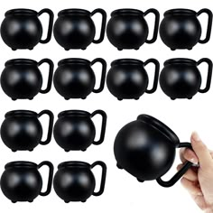 a hand is holding a black coffee mug in front of a set of 12 kettles