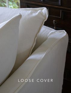 a close up of a white pillow on a couch with the words loose linens written below it