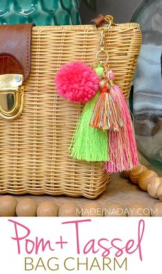 a wicker purse with pom - tassels hanging from it