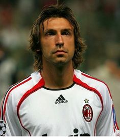 a man with long hair wearing a white and red soccer uniform looking off to the side