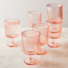 four pink glass cups sitting on top of a marble countertop next to each other