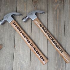 two hammers sitting next to each other on top of a wooden floor with words written on them