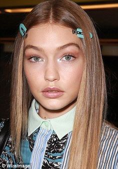 a woman with long blonde hair and blue eyeshades on her head, wearing a striped jacket