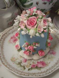 a blue and white cake with pink flowers on it sitting on a plate next to other plates