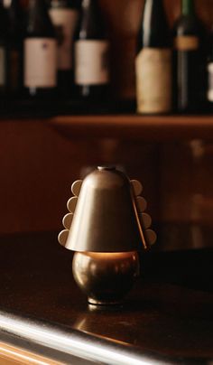 a small lamp sitting on top of a counter next to some bottles and wine glasses