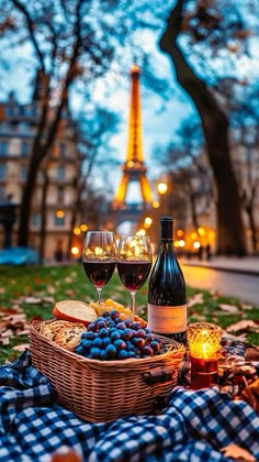 two glasses of wine, bread and grapes on the ground in front of the eiffel tower