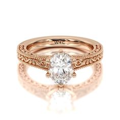 a rose gold engagement ring with an oval center stone and filigrees on the band