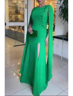 a woman wearing a green dress and cape standing in front of a store display window