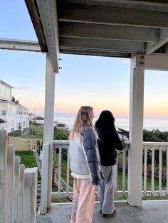 two women standing on a porch looking out at the ocean