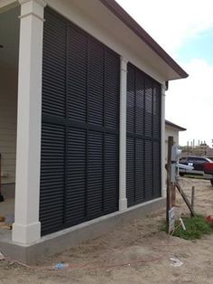 a man standing in front of a building with black shutters on the side of it