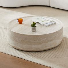 a coffee table sitting on top of a rug in front of a white couch next to a book